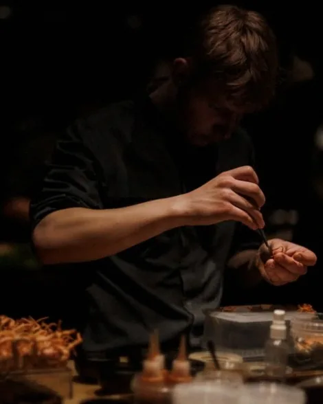 A chef plating with tweezers in the kitchen